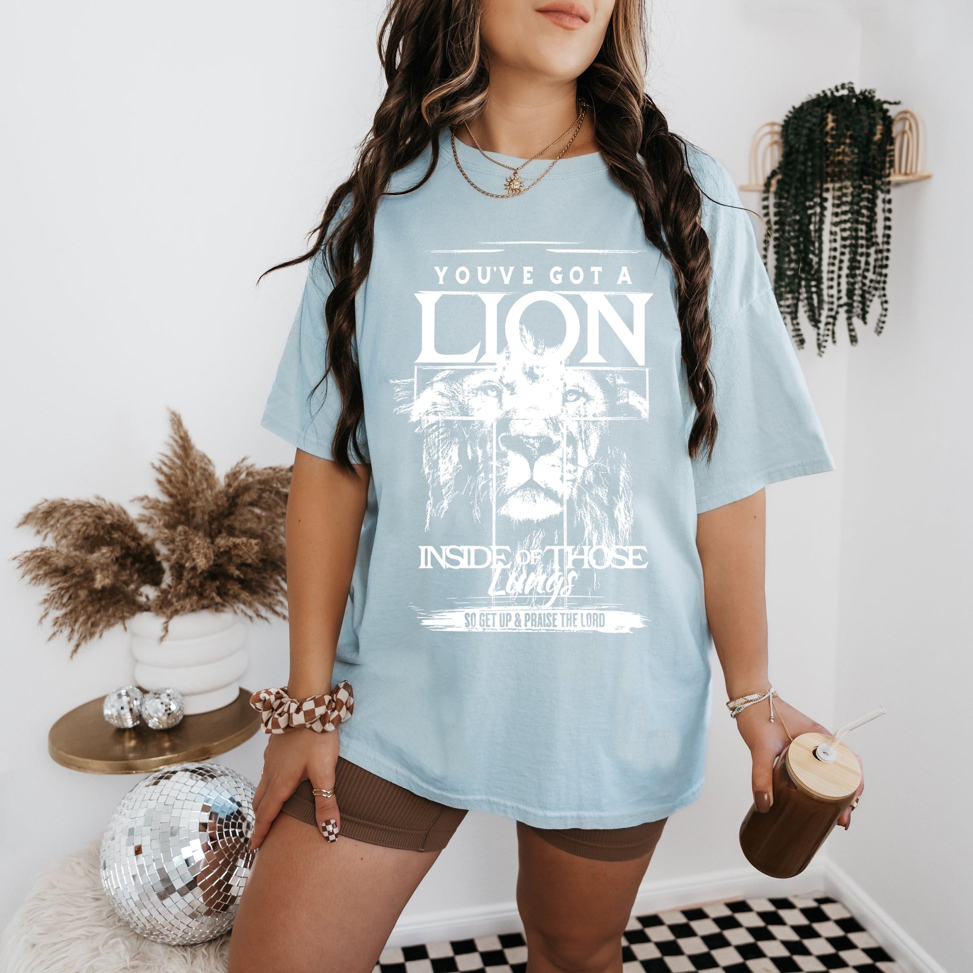a woman standing in a room with a lion t - shirt on
